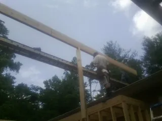 Carpenter setting a ridge beam over a new addition frame — Ice Dam Removal by Roofing Brothers in Aliceville