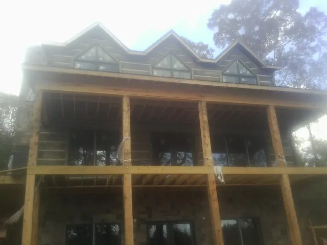 Dormers and porch framing on a large log home under construction — Roof Coating work by our crew in Aliceville