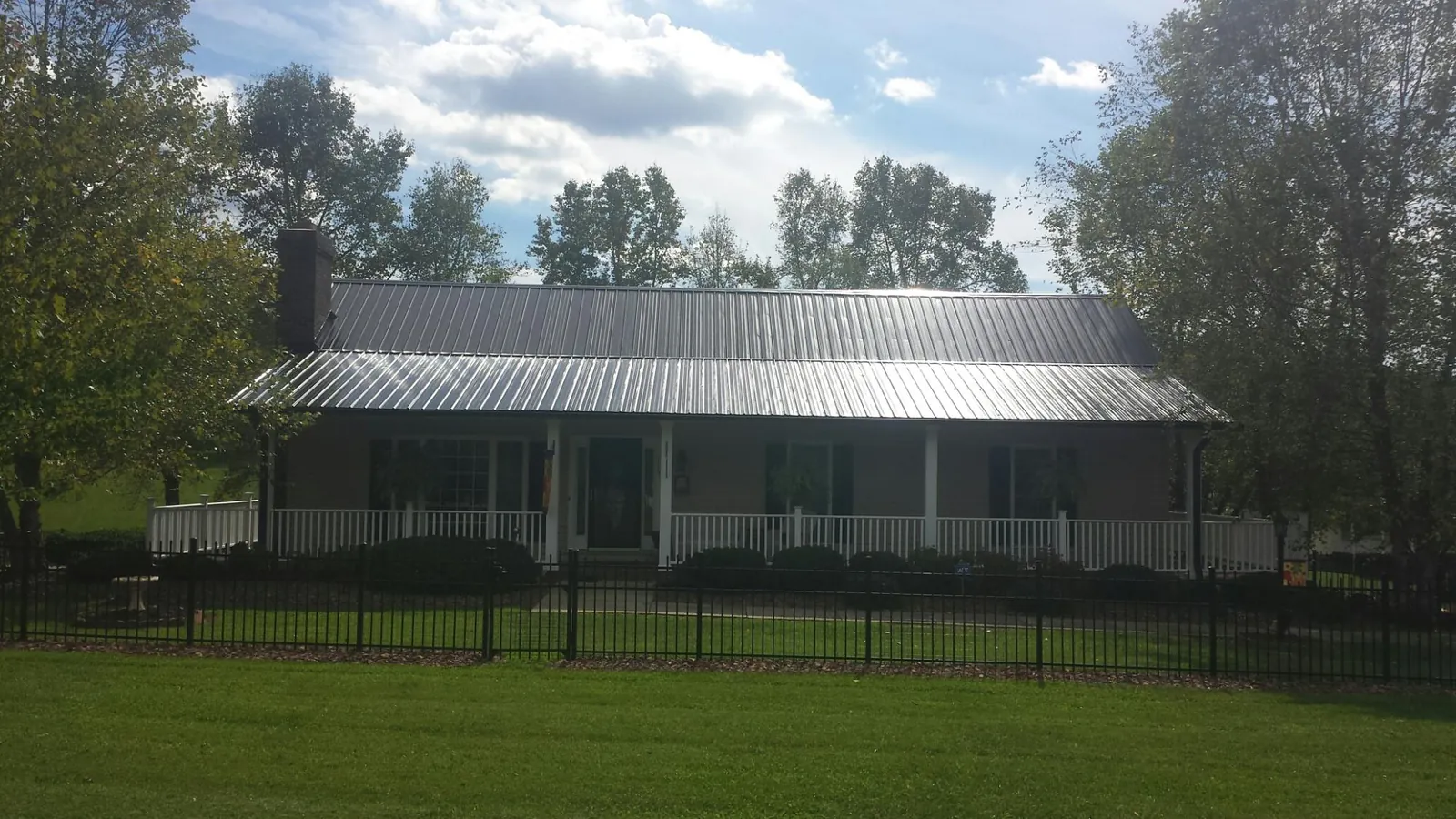 Gray metal roof on a brick ranch with a full width front porch — Gutter Guard Installation work by our crew in Aliceville