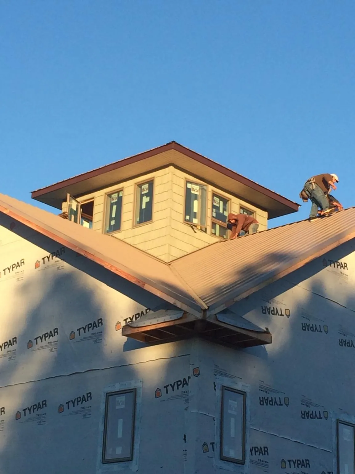 Roofers working around a rooftop cupola on a new metal roof at sunset — Roof Waterproofing in Aliceville by Roofing Brothers